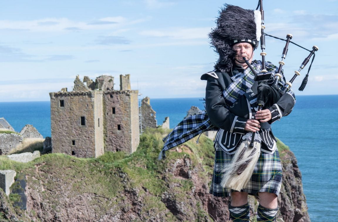 Gaiteiro con traxe típico escocés no castelo de Dunnottar